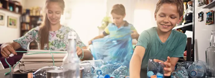 Los niños clasifican las botellas de plástico para reciclarlas en casa.