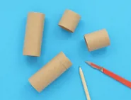 Cinco tubos de papel higiénico cortados en diferentes tamaños junto a unas tijeras y un lápiz.