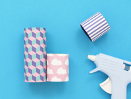 Três tubos de papel higiénico decorados com pistola de cola quente ao lado.