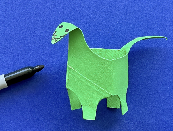 Una madre y su hija haciendo manualidades de animales con rollos de papel higiénico en el escritorio.