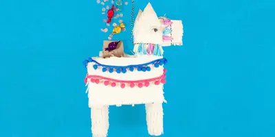 Piñata de llama blanca cubierta con papel de seda con flecos y dulces que caerán de la parte superior