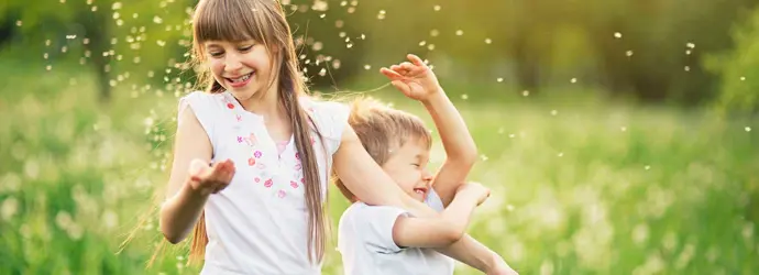 Hermano y hermana jugando en un campo de diente de león rodeado por el polen