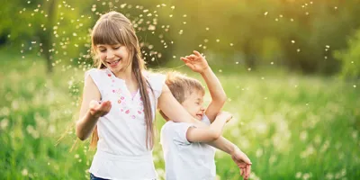 Hermano y hermana jugando en un campo de diente de león rodeado por el polen