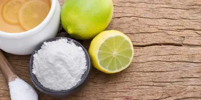 Productos de limpieza ecológicos como el limón, la lima, y el bicarbonato de sodio en una tabla de cortar de madera