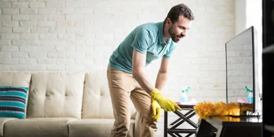 Hombre quitando el polvo de su casa con un plumero