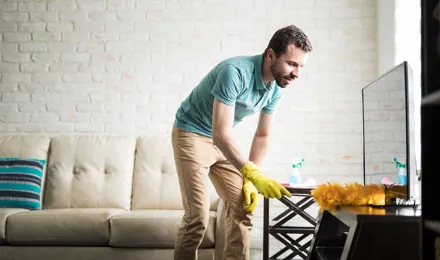 Hombre quitando el polvo de su casa con un plumero