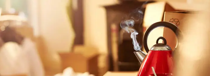 Un hervidor de agua rojo y limpio hirviendo en la encimera de la cocina