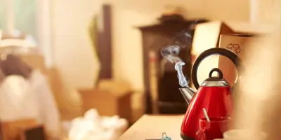 Un hervidor de agua rojo y limpio hirviendo en la encimera de la cocina