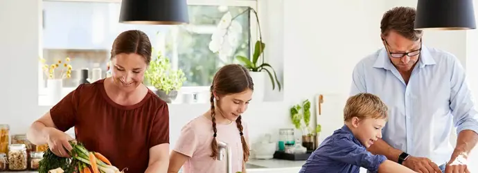 Una madre y un padre enseñando reciclaje para niños, desempaquetando comida de envases reciclables en una cocina