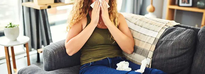 Mulher com sintomas de alergia ou constipação a assoar o nariz
