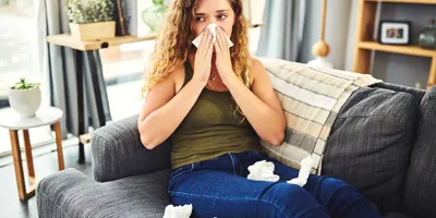 Mulher com sintomas de alergia ou constipação a assoar o nariz