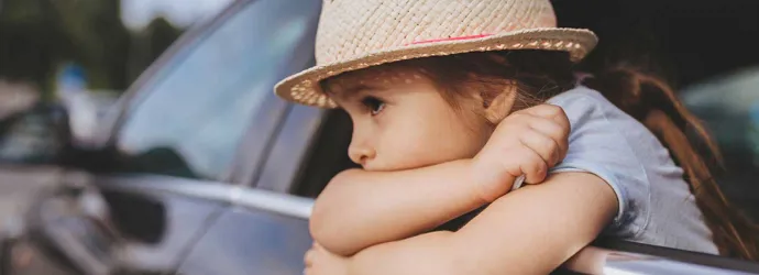 Criança enjoada num carro a usar um chapéu