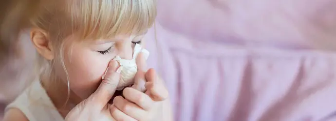 Mãe a ajudar a filha a assoar o nariz com lenço de papel