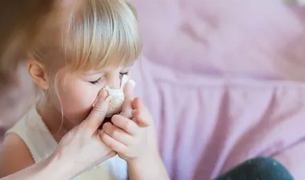 Mãe a ajudar a filha a assoar o nariz com lenço de papel