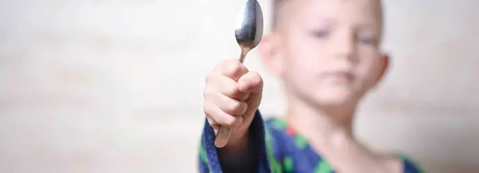 Um jovem a segurar uma colher de prata