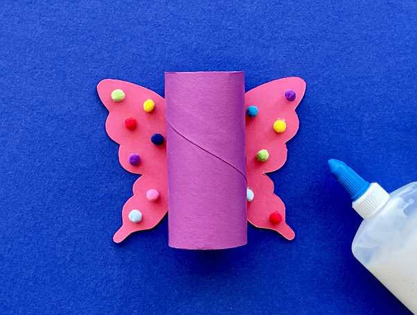 Una madre y su hija haciendo manualidades de animales con rollos de papel higiénico en el escritorio.