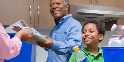 El abuelo enseña a un niño a reciclar en la cocina.