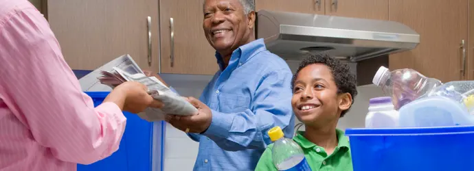 El abuelo enseña a un niño a reciclar en la cocina.