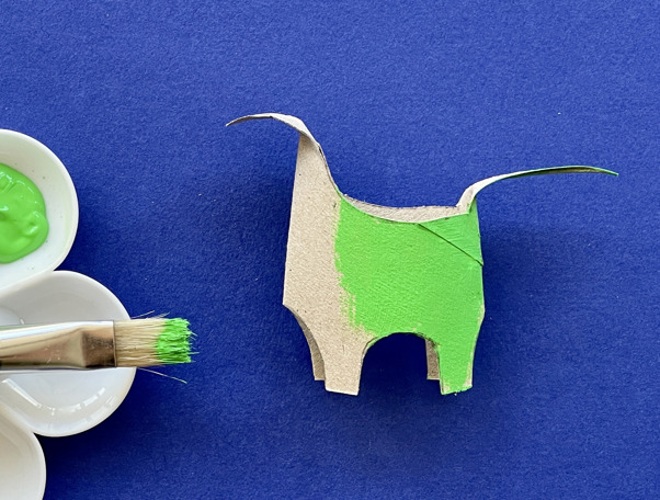 Una madre y su hija haciendo manualidades de animales con rollos de papel higiénico en el escritorio.