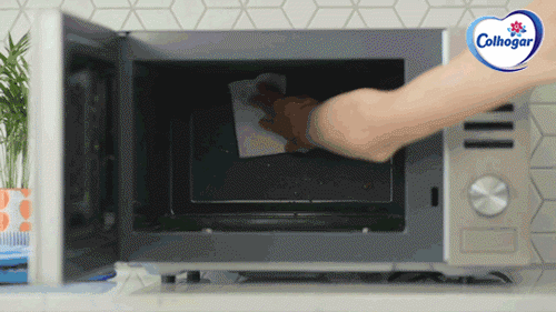 Un GIF de unas manos limpiando el interior de un microondas con papel de cocina y bicarbonato de sodio.