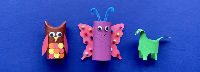 Una madre y su hija haciendo manualidades de animales con rollos de papel higiénico en el escritorio.