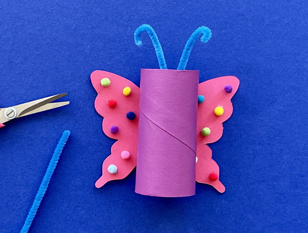 Una madre y su hija haciendo manualidades de animales con rollos de papel higiénico en el escritorio.