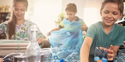 As crianças seleccionam garrafas de plástico para reciclagem em casa.