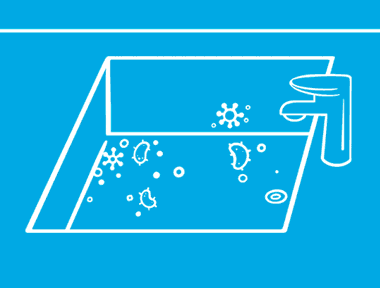 Unas manos sobre un fondo azul rociando y limpiando bacterias del interior de un fregadero.