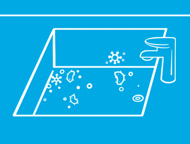 Unas manos sobre un fondo azul rociando y limpiando bacterias del interior de un fregadero.